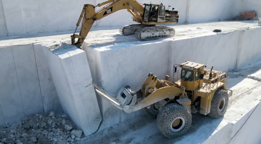 Cutting marble into blocks by excavator and wheel loader