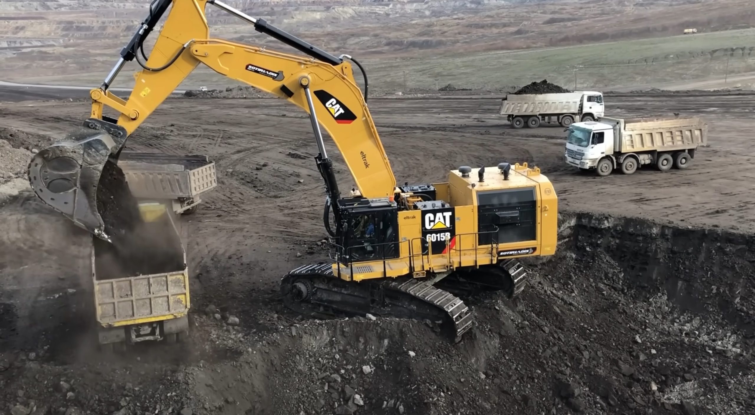 Caterpillar 6015B Excavator Loading Trucks with coal at coal mine with 2 trucks