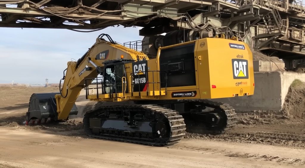 Excavator on its way to mine passing under conveyor belt