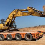 Excavator on top of heavy duty trailer with boom straight