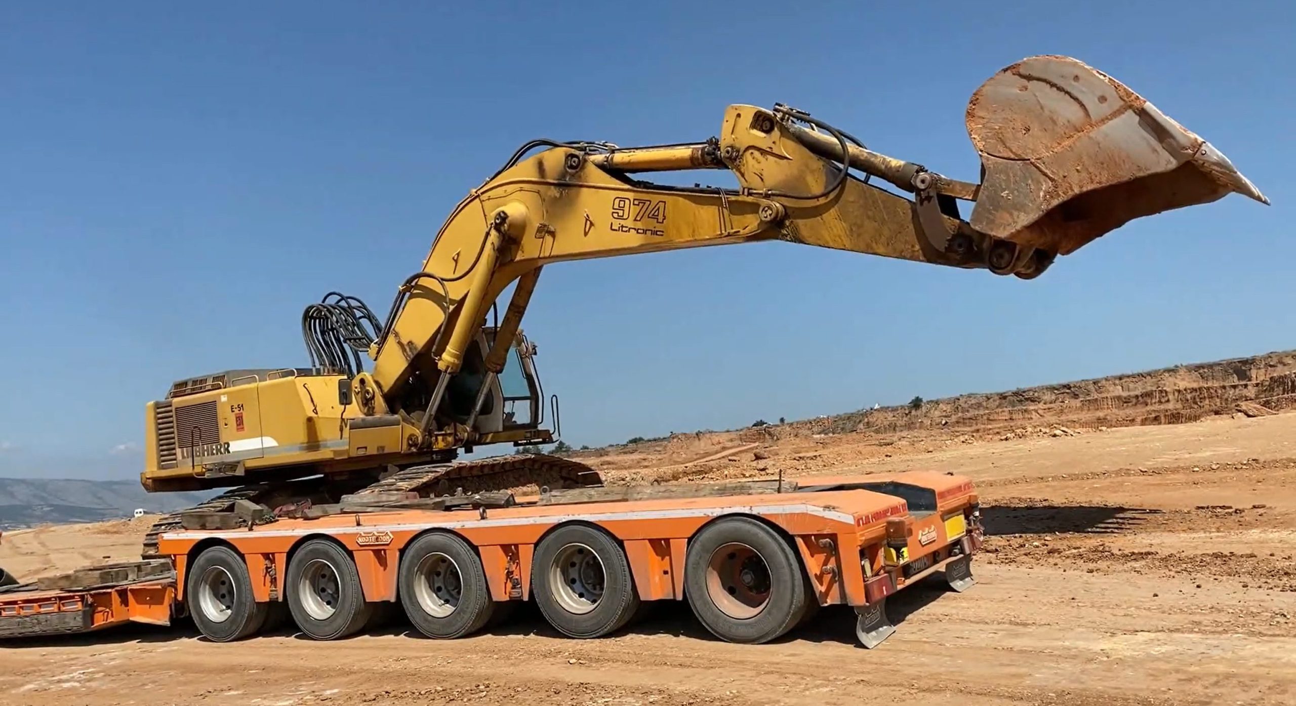 Excavator on top of heavy duty trailer with boom straight