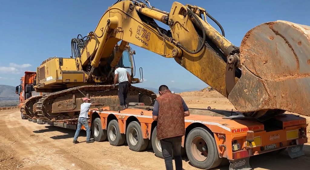 Excavator on top of heavy duty trailer with boom straight