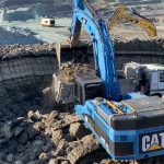 Blue Caterpillar 345C excavator loading coal on trucks