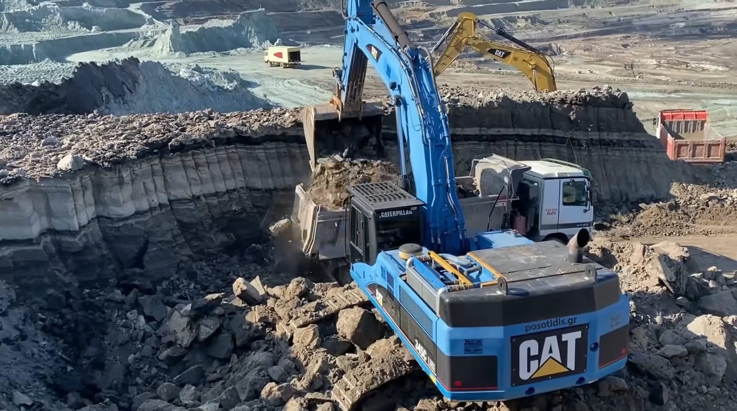 Blue Caterpillar 345C excavator loading coal on trucks