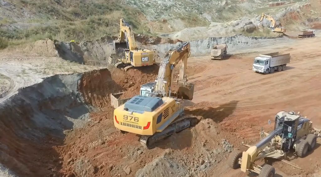 Excavator working on mine with other heavy machines