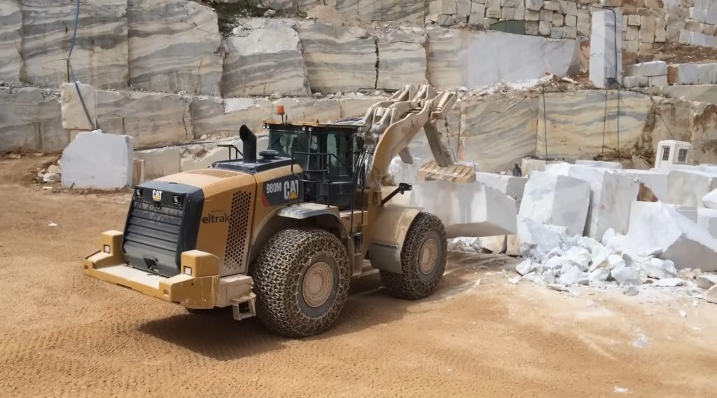 Wheel loader droping marble block in order to crush