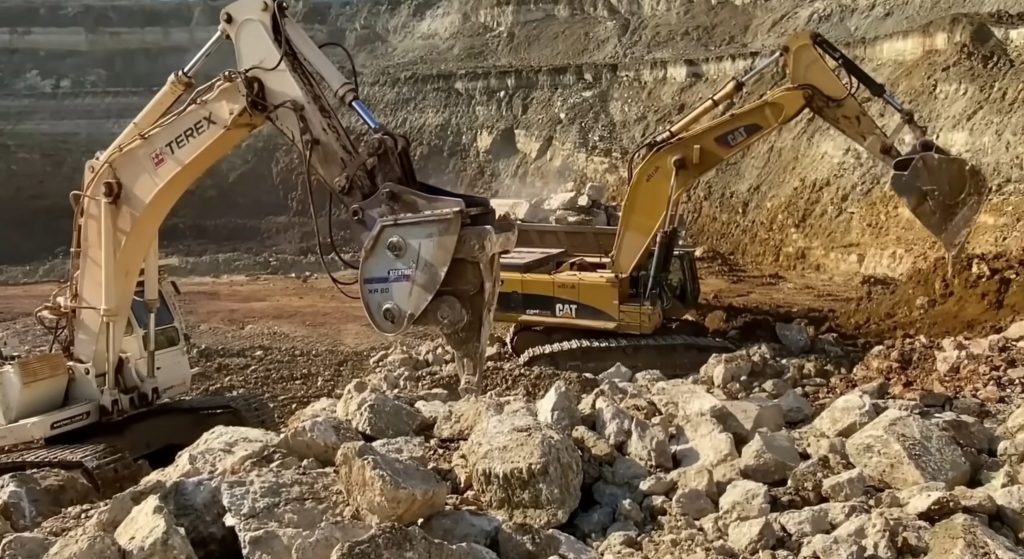 Hydraulic ripper and excavator working on quarry