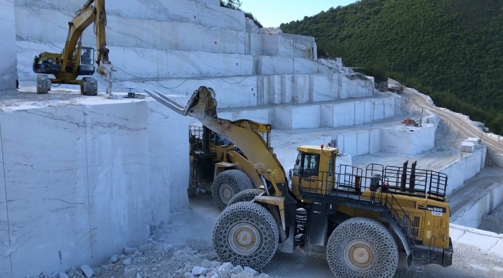 Wheel loader helping excavator extracting marble column