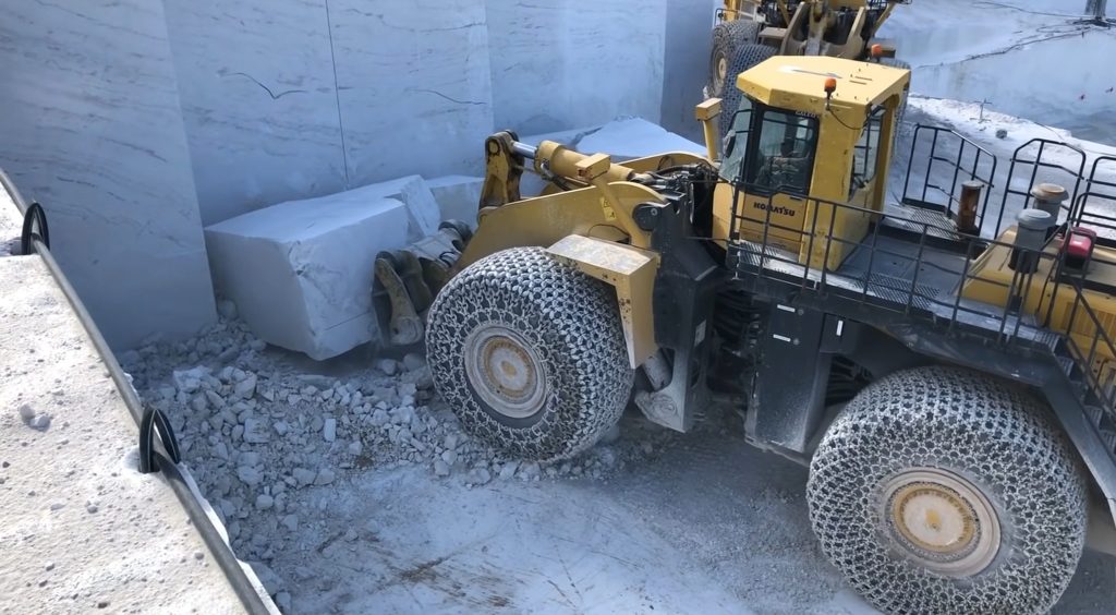 Wheel loader lifting a marble piece for transporting