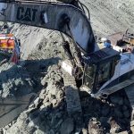 White Caterpillar excavator working and digging overburden