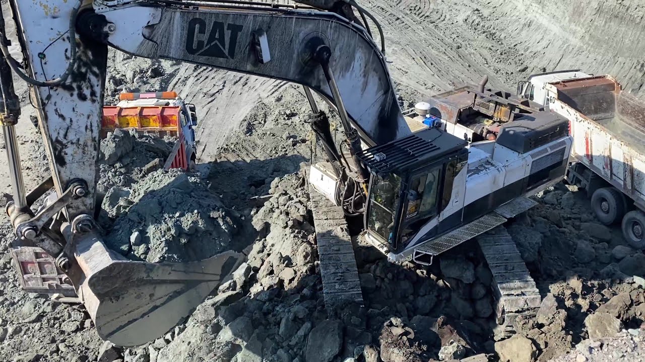 White Caterpillar excavator working and digging overburden