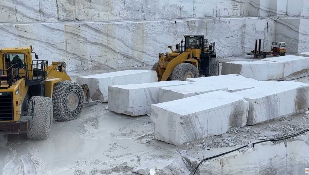 Wheel loaders moving marble piece to storage