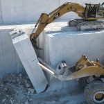 Wheel loader helping excavator dropping marble column