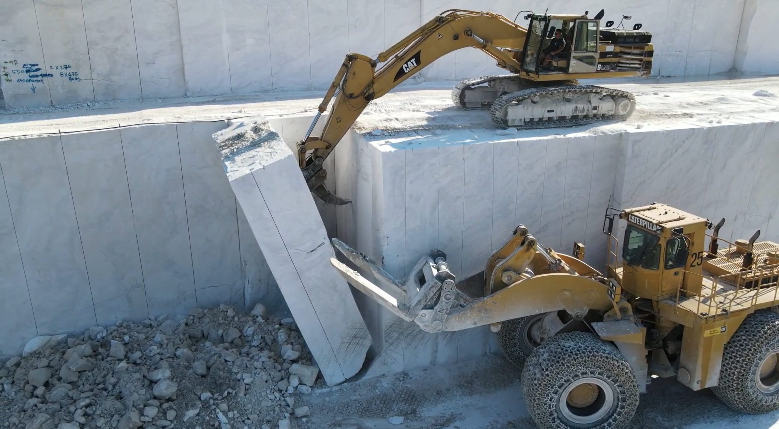 Wheel loader helping excavator dropping marble column